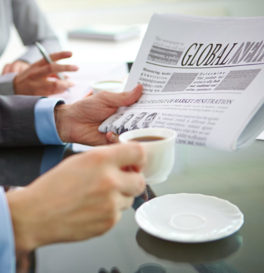 Businessman with newspaper having coffee at workplace